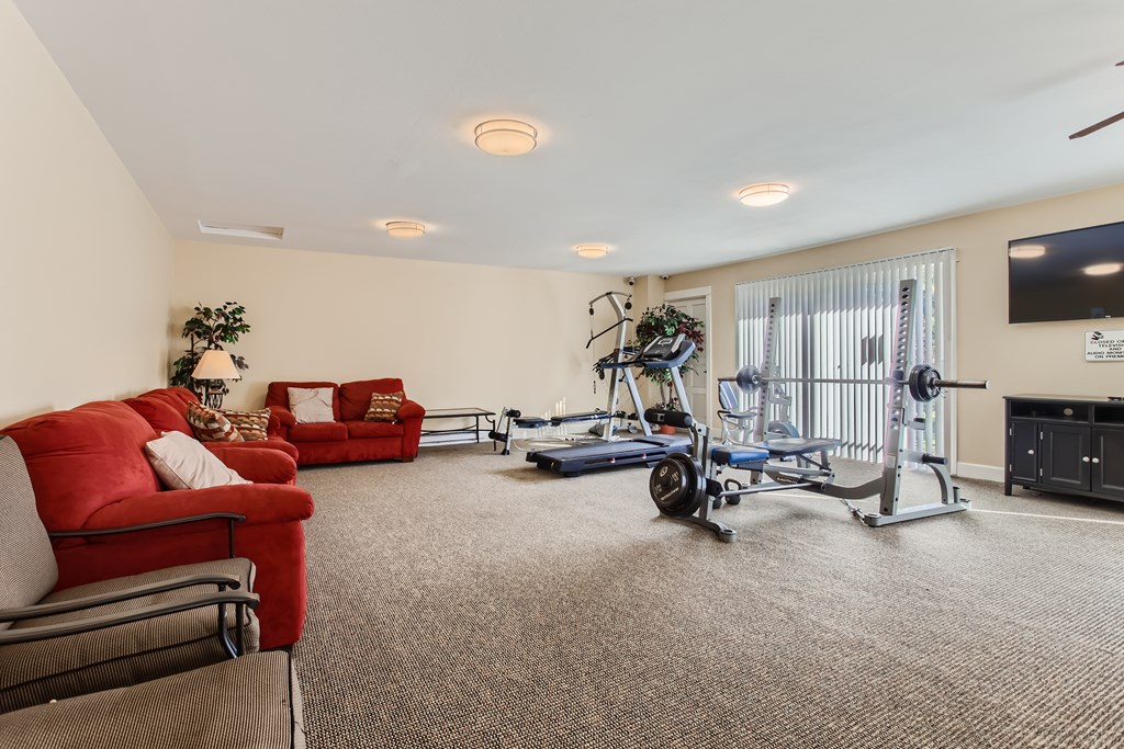 A living room with a red couch, a blue exercise bike, and a TV.