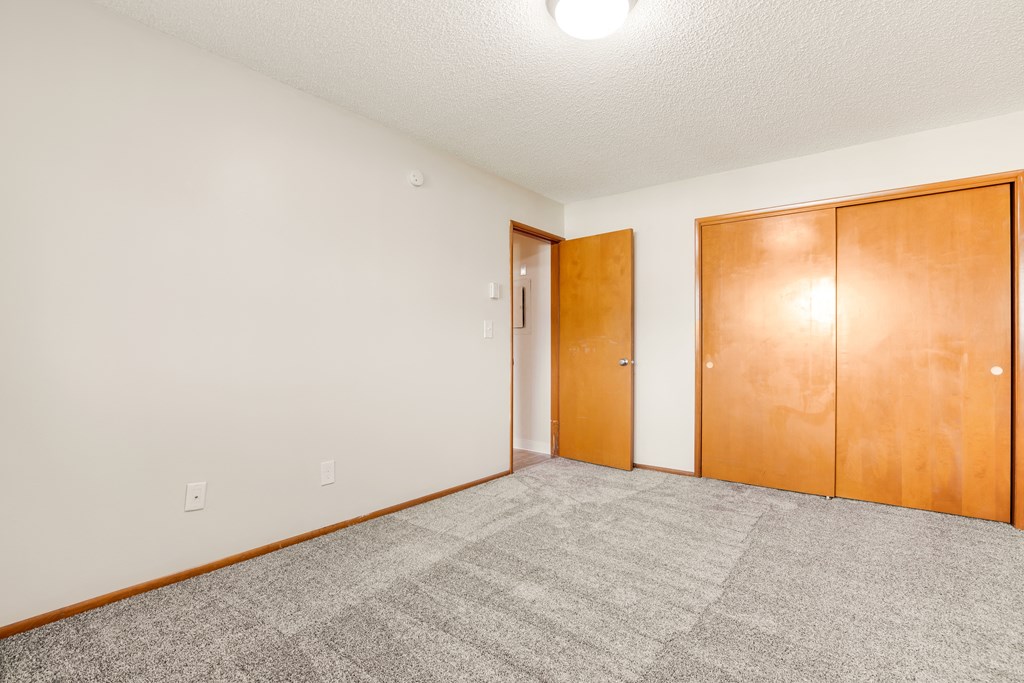 a empty living room with carpet and wood doors