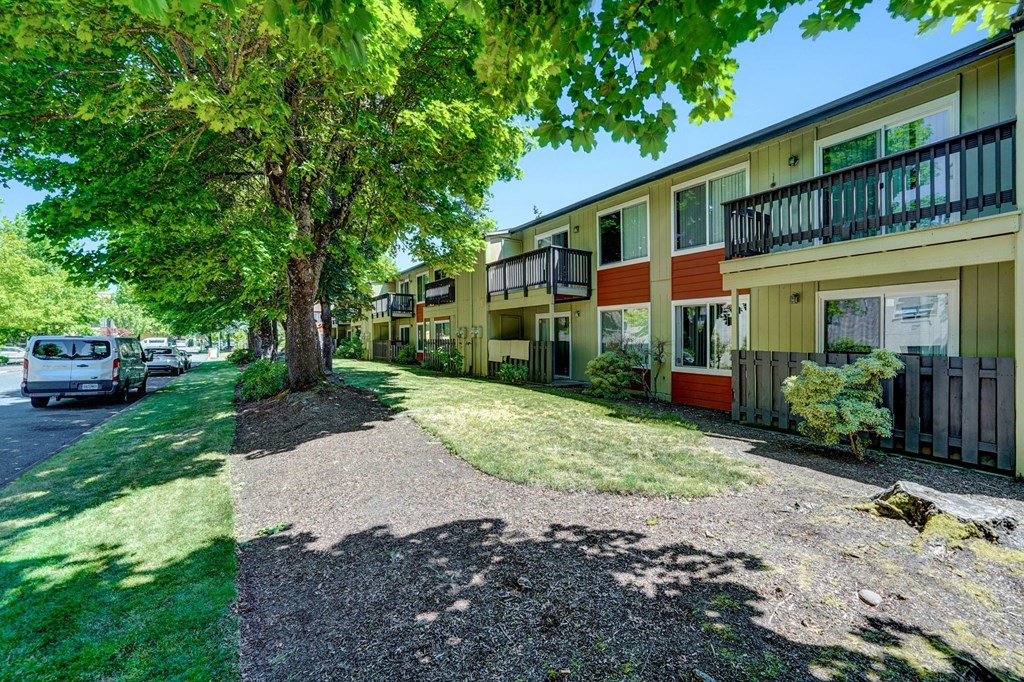 a street view of a row of townhomes with cars parked on the side of the