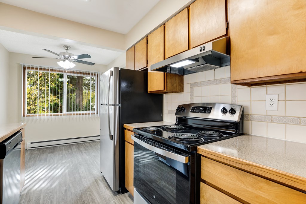 an updated kitchen with black appliances and wood cabinets