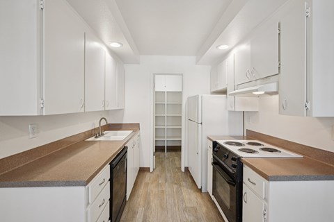 A kitchen with white cabinets and a brown counter top.