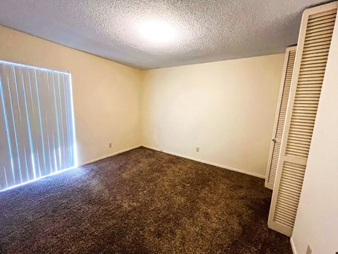 A room with a carpeted floor and a window with blinds.