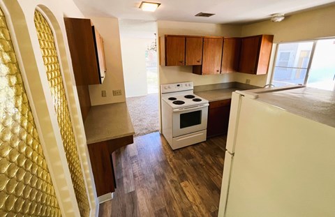 A kitchen with a white stove and wooden floors.
