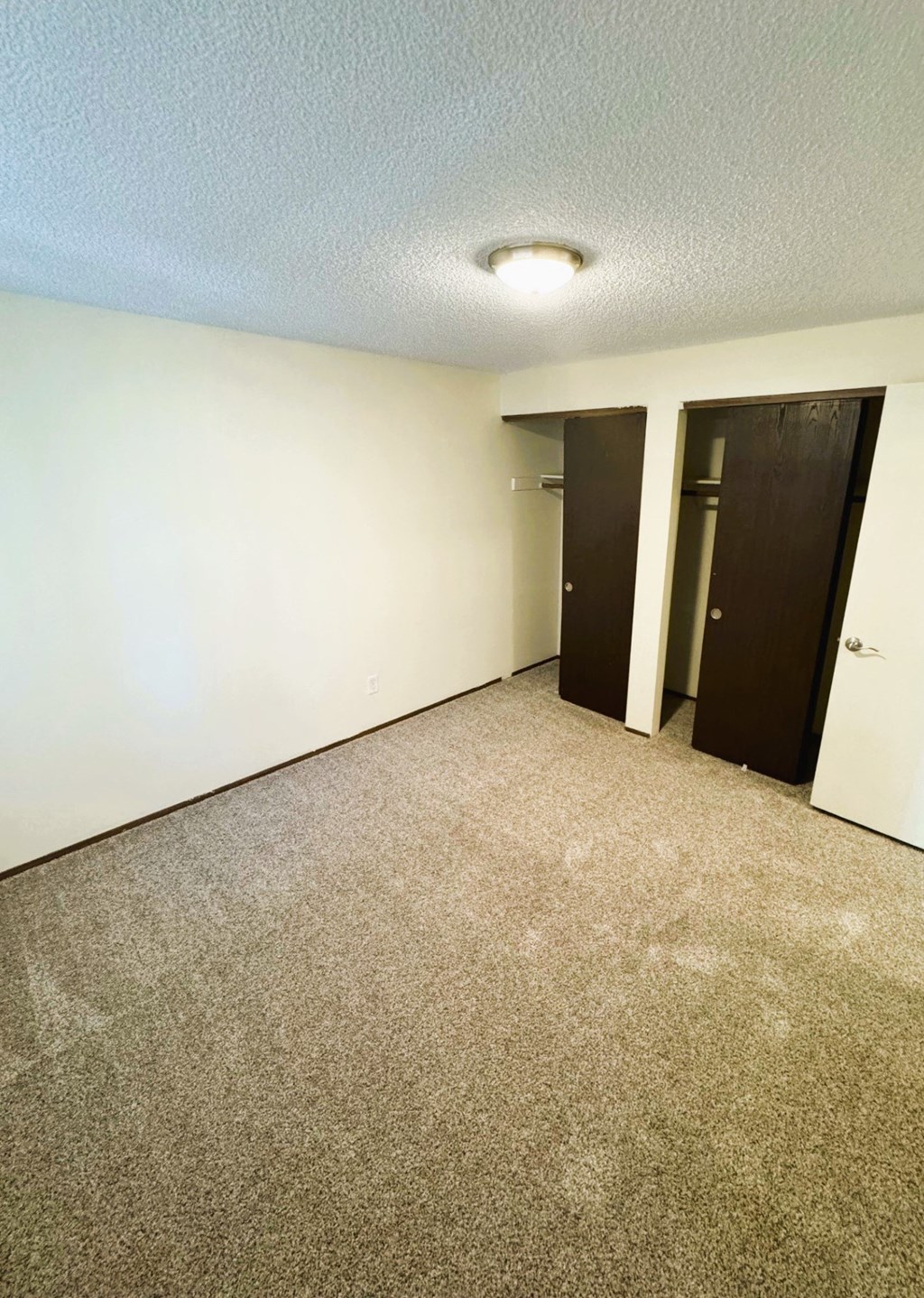 A room with carpeted floor and two doors.