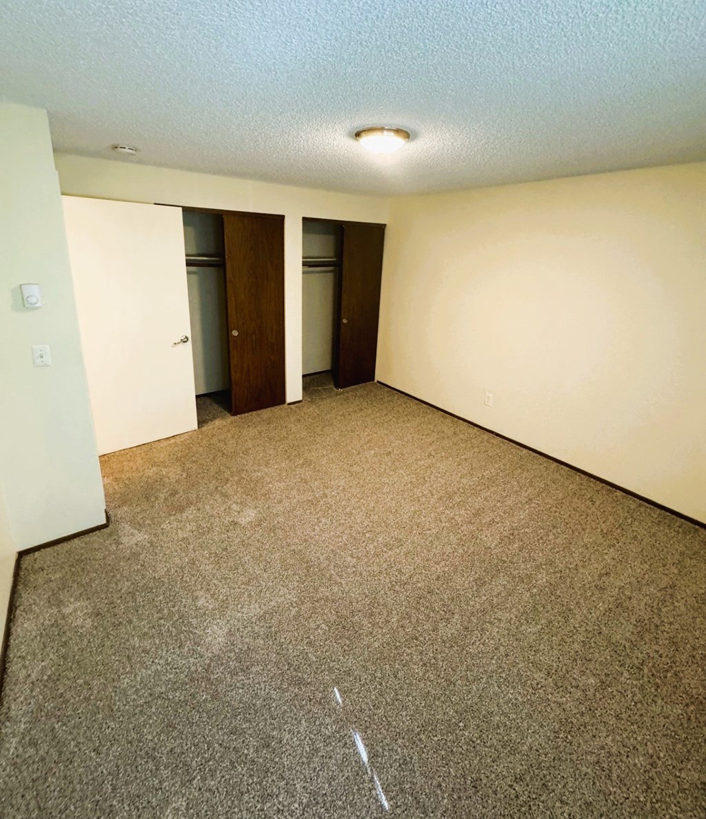 A room with carpeted floor and two doors.