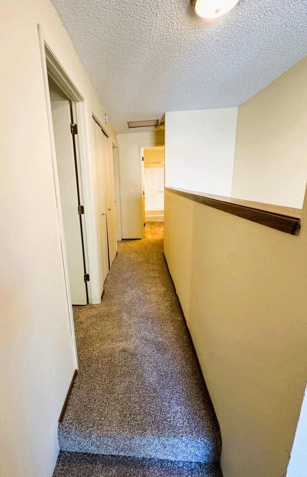 A hallway with a carpeted floor and white walls.