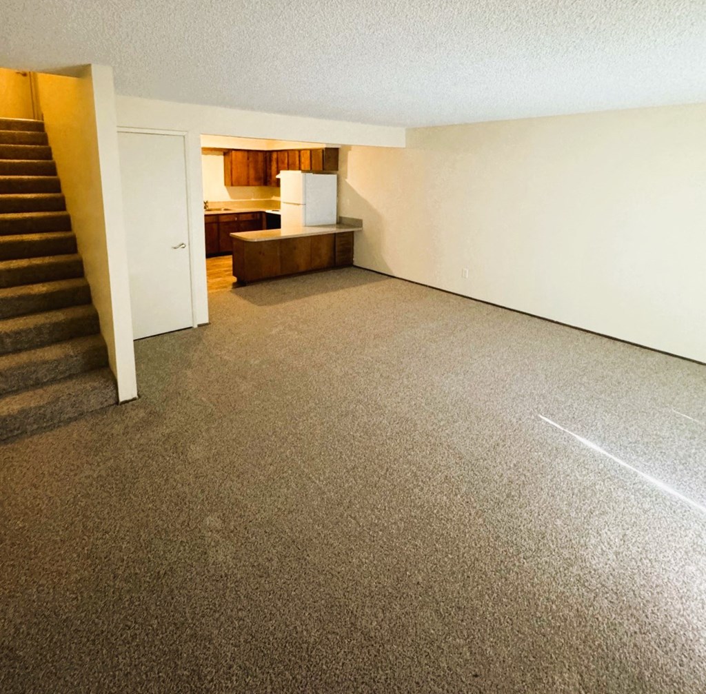 A room with a staircase leading to a kitchen area.