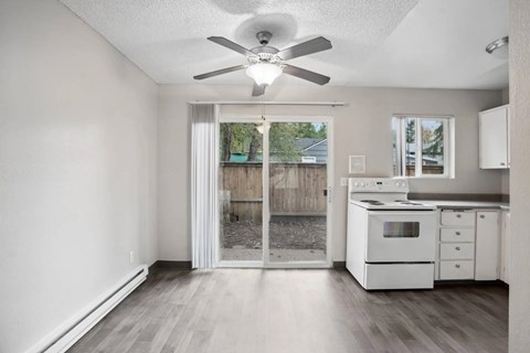 A white kitchen with a fan and a sliding glass door.