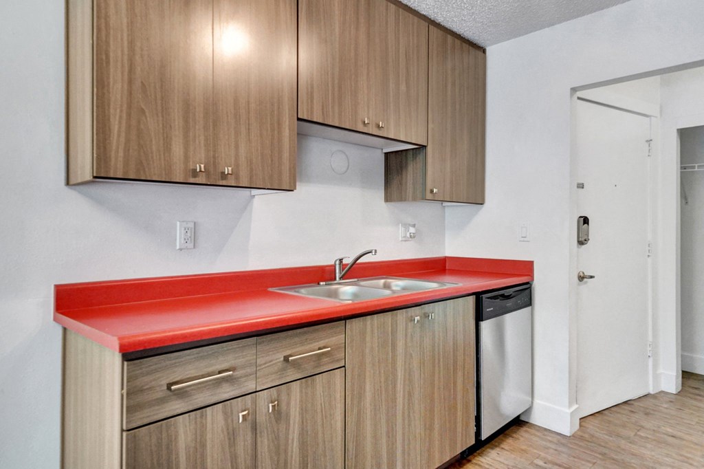 a kitchen with a red counter top and wooden cabinets