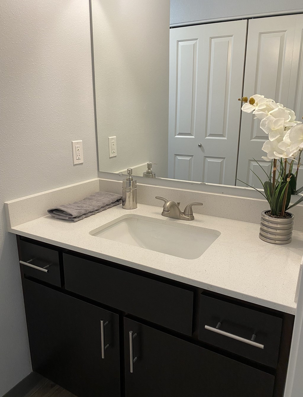 A bathroom with a sink, mirror, and black cabinets.