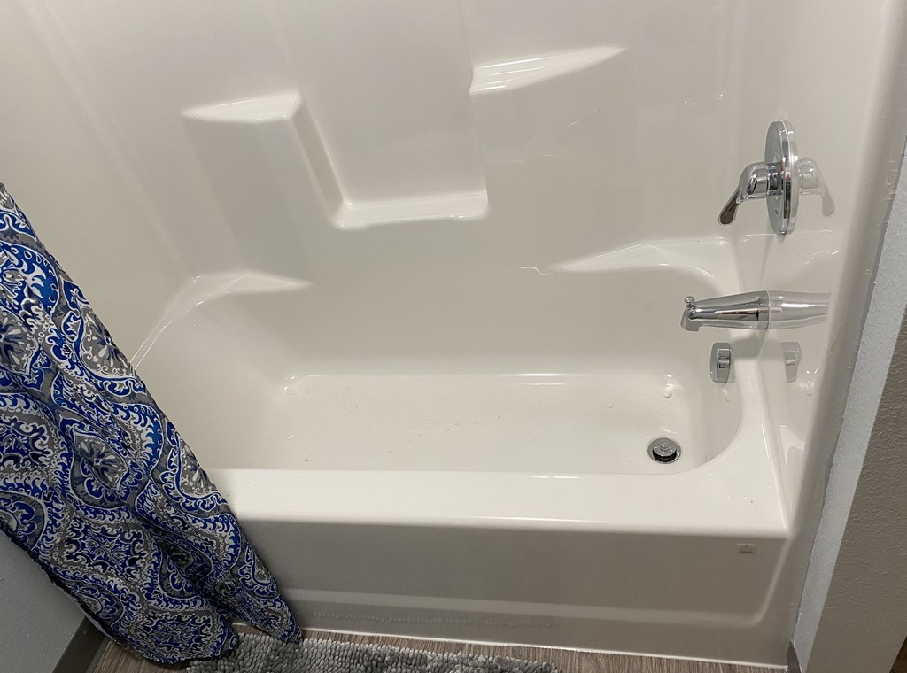 A white bathtub with a silver faucet and a blue and white towel hanging on the side.