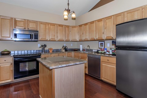A kitchen with wooden cabinets and a stainless steel refrigerator.