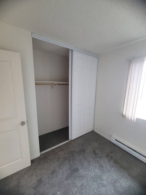 A room with a white door and a window with white curtains.