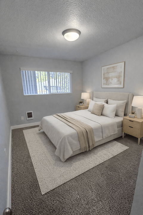 A bedroom with a bed, nightstand, and window.