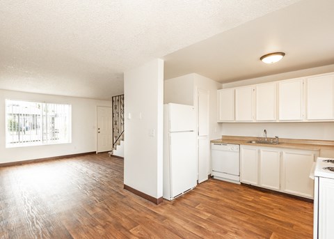A kitchen with white cabinets and a wooden floor.