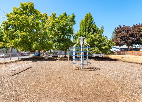 A playground with a swing set in the middle of a gravel area.