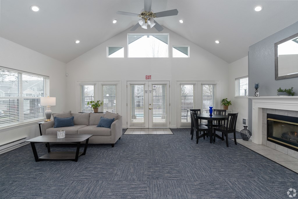 A living room with a grey carpet and a fireplace.