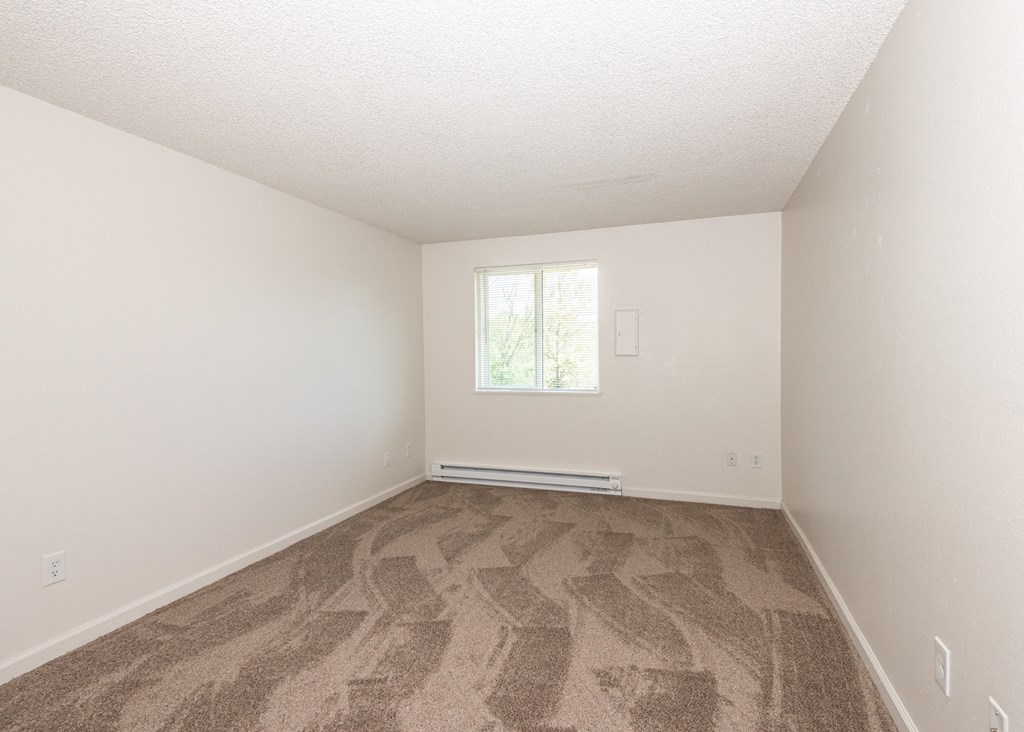 a bedroom with white walls and a window