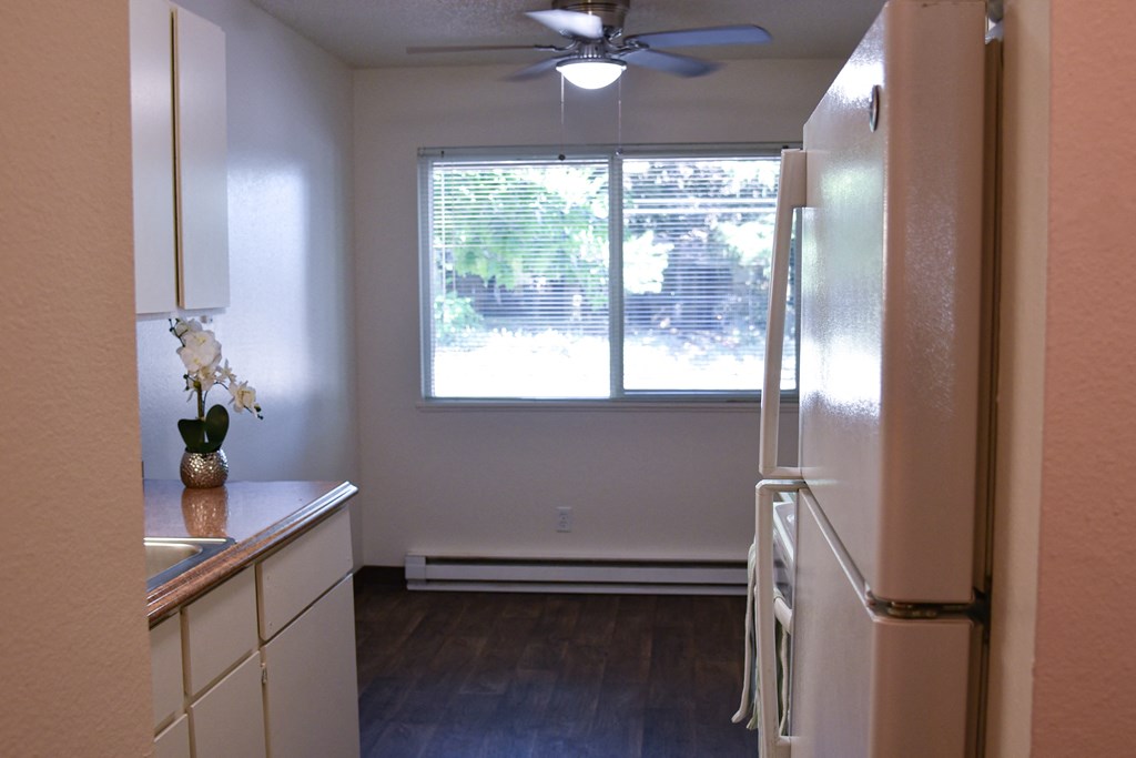 a kitchen with white appliances and a large window