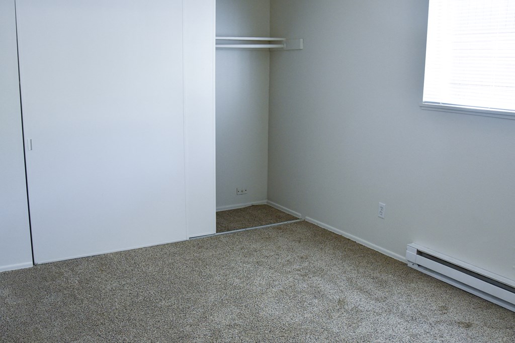 an empty room with a closet and a window