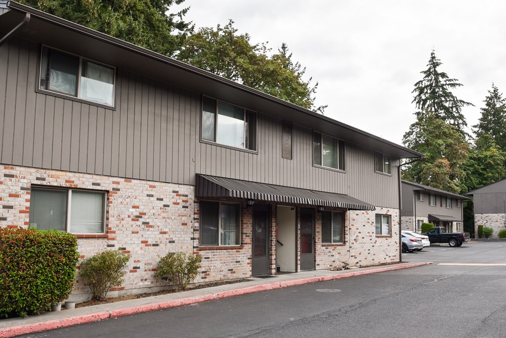 A building with a grey roof and a brick wall with a car parked in front.
