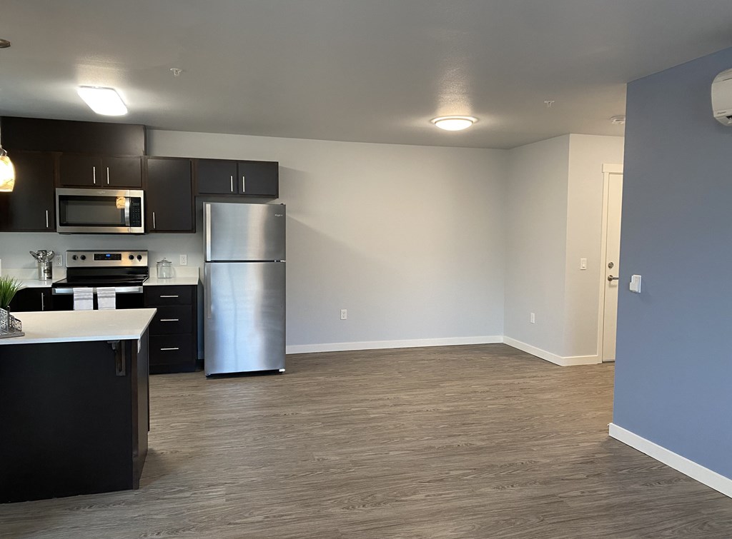 A kitchen with black cabinets and a stainless steel refrigerator.