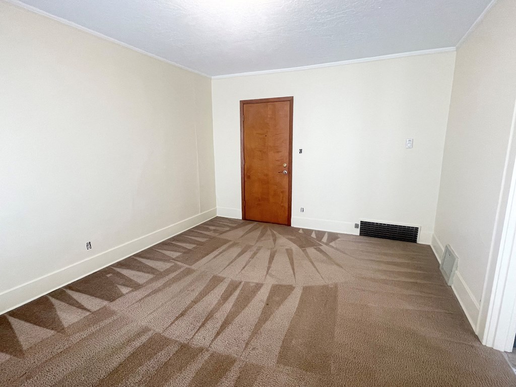 an empty room with white walls and a brown carpet