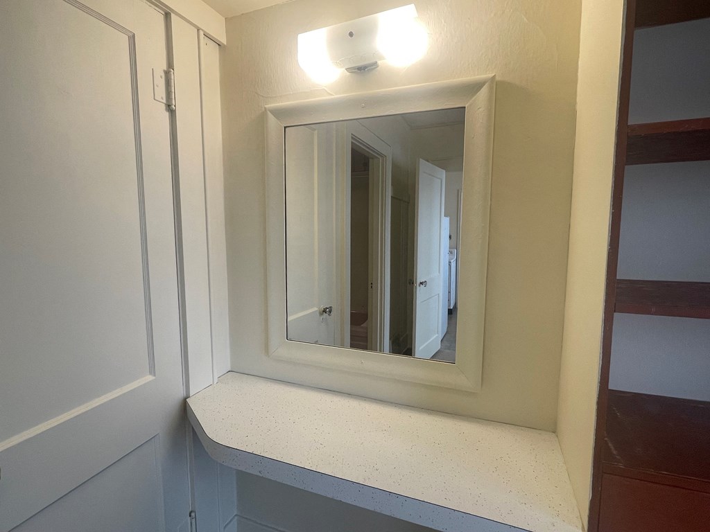 a small shelf in the corner of a room with a mirror
