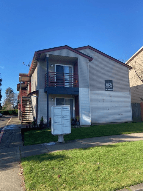 A two-story apartment building with a garage door on the first floor.