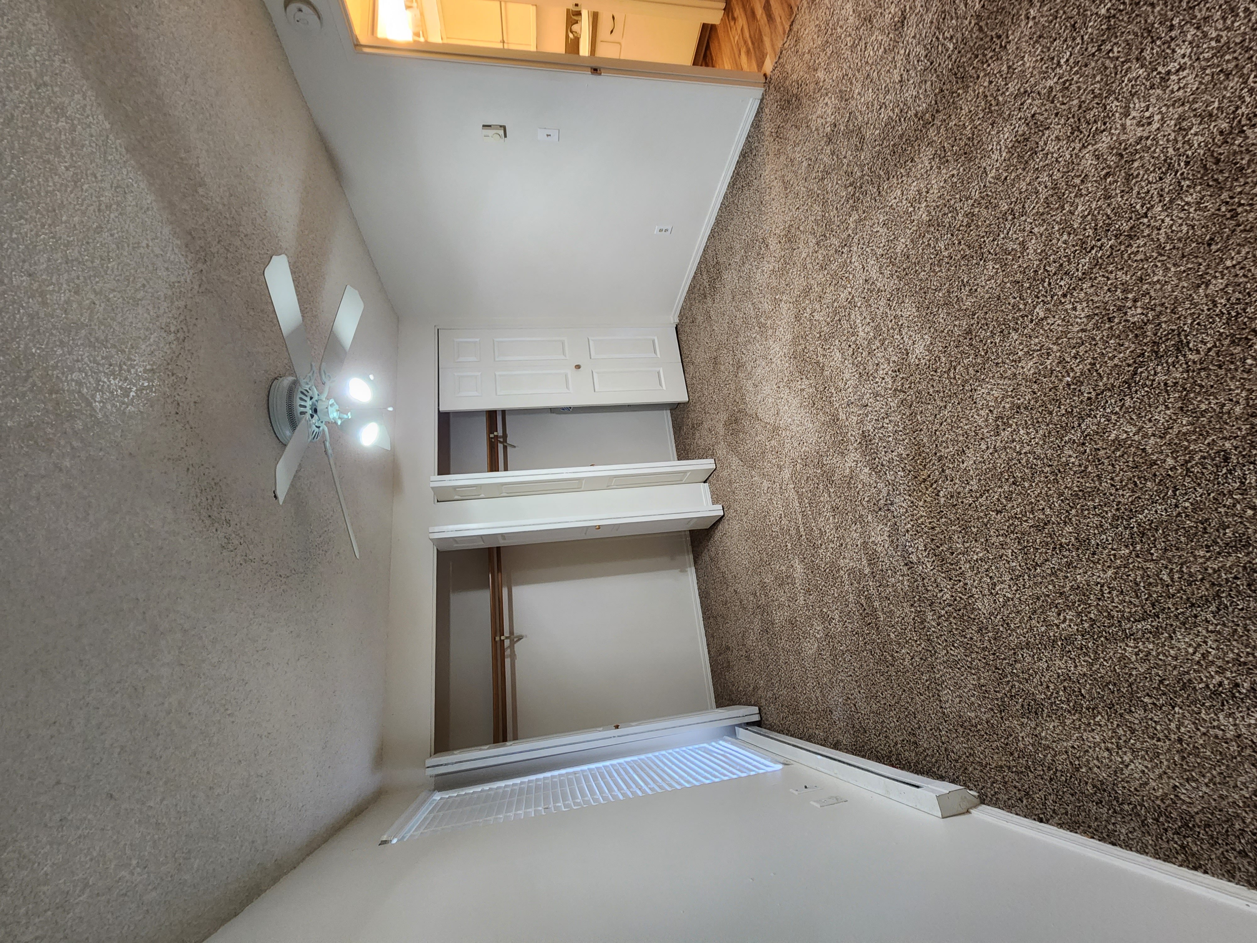 a bedroom with a large window and a ceiling fan