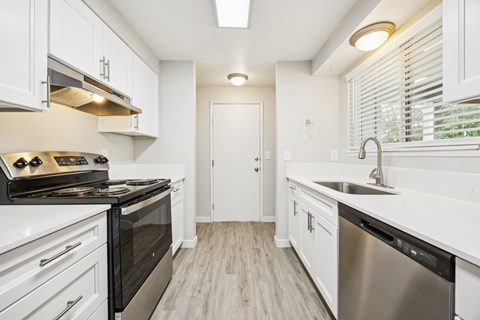 A modern kitchen with white cabinets and stainless steel appliances.