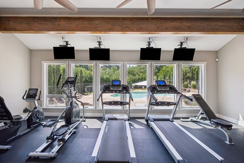 A gym with treadmills, exercise bikes, and a ceiling fan.