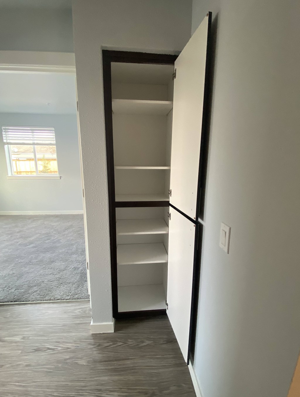 A white door with a black frame is open to a room with a carpeted floor.