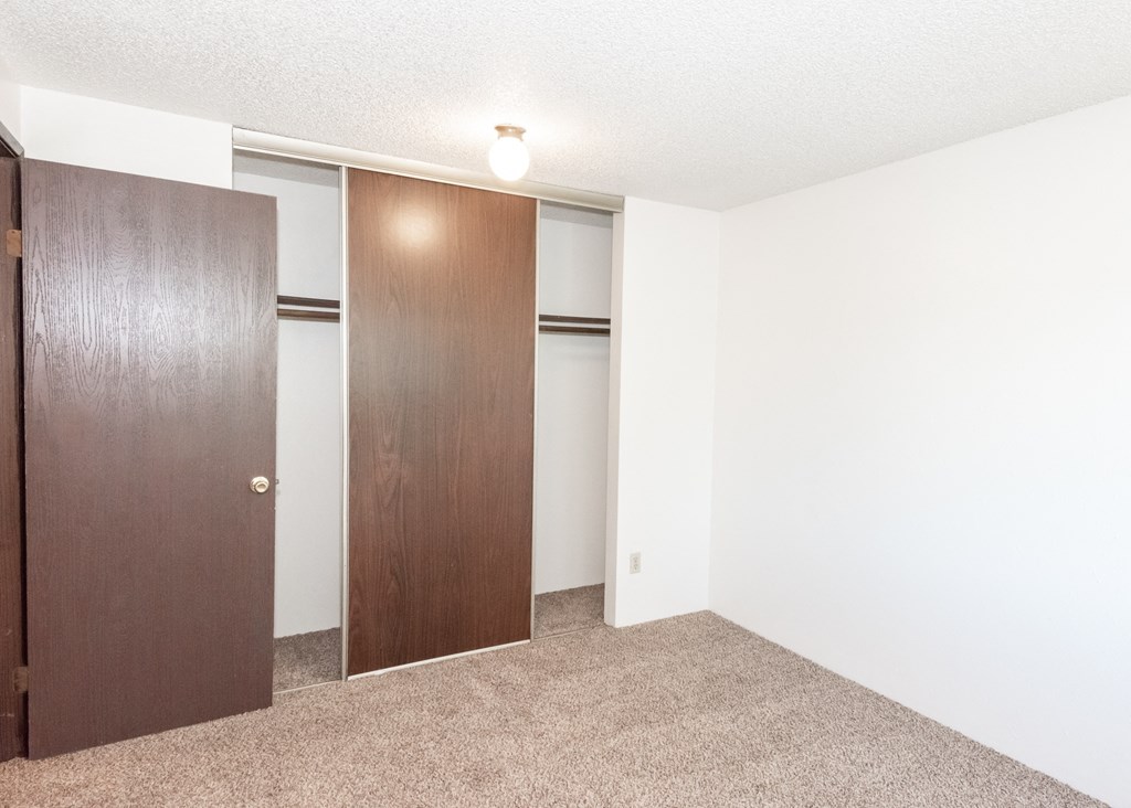 a bedroom with a door to a closet and a carpeted floor