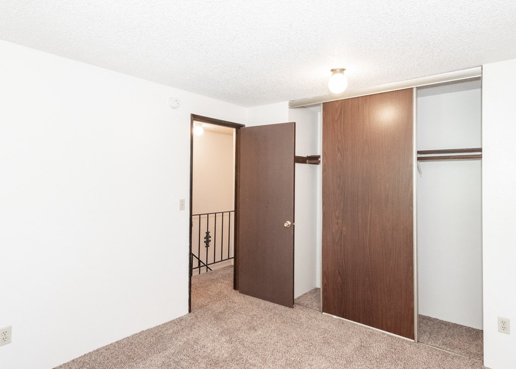 a bedroom with a door to a hallway and a carpeted floor