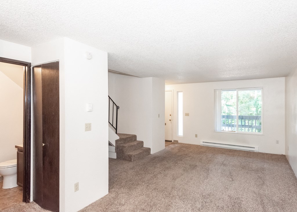 a bedroom with a large window and a carpeted floor