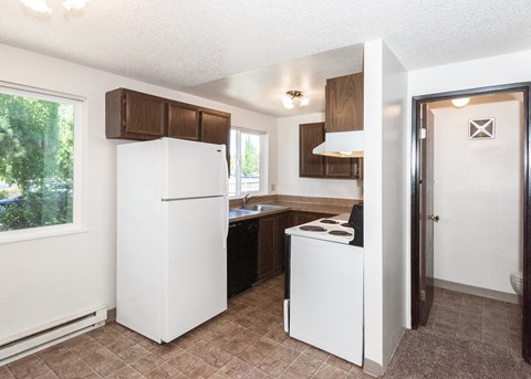 an empty kitchen with a white refrigerator and a window