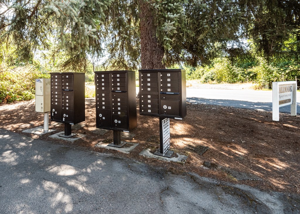 a group of three metal boxes sit under a tree on the side of a road