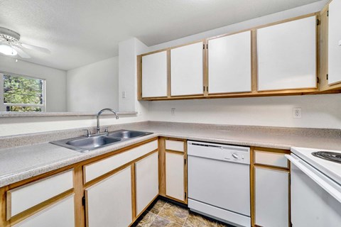 A kitchen with white cabinets and a white dishwasher.