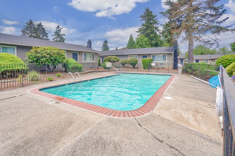 A swimming pool surrounded by a concrete patio and a metal fence.