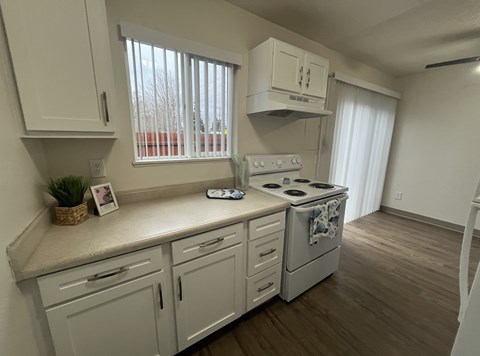 A kitchen with white cabinets and a stove top oven.