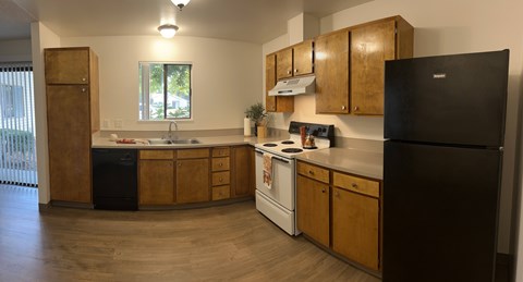 A kitchen with wooden cabinets and a black refrigerator.