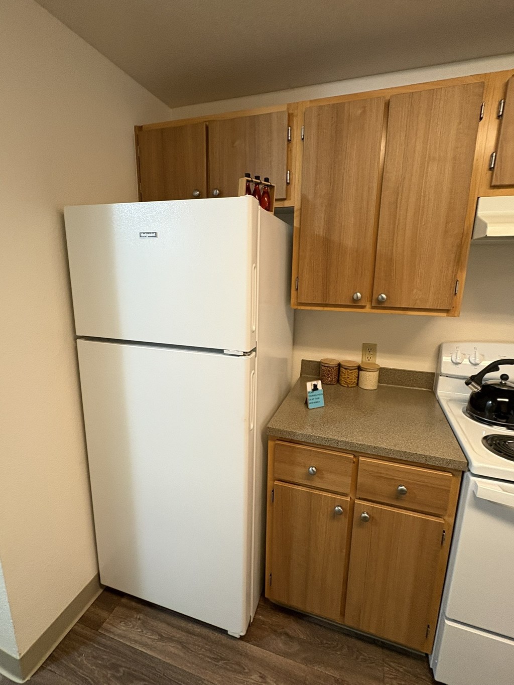 A white refrigerator stands next to a stove in a kitchen.