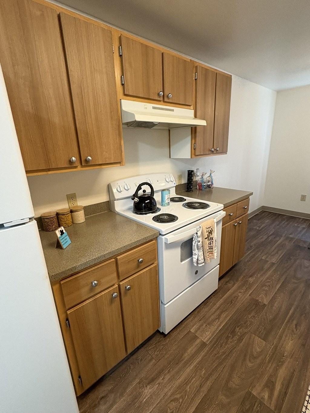 A kitchen with a white stove top oven and wooden cabinets.