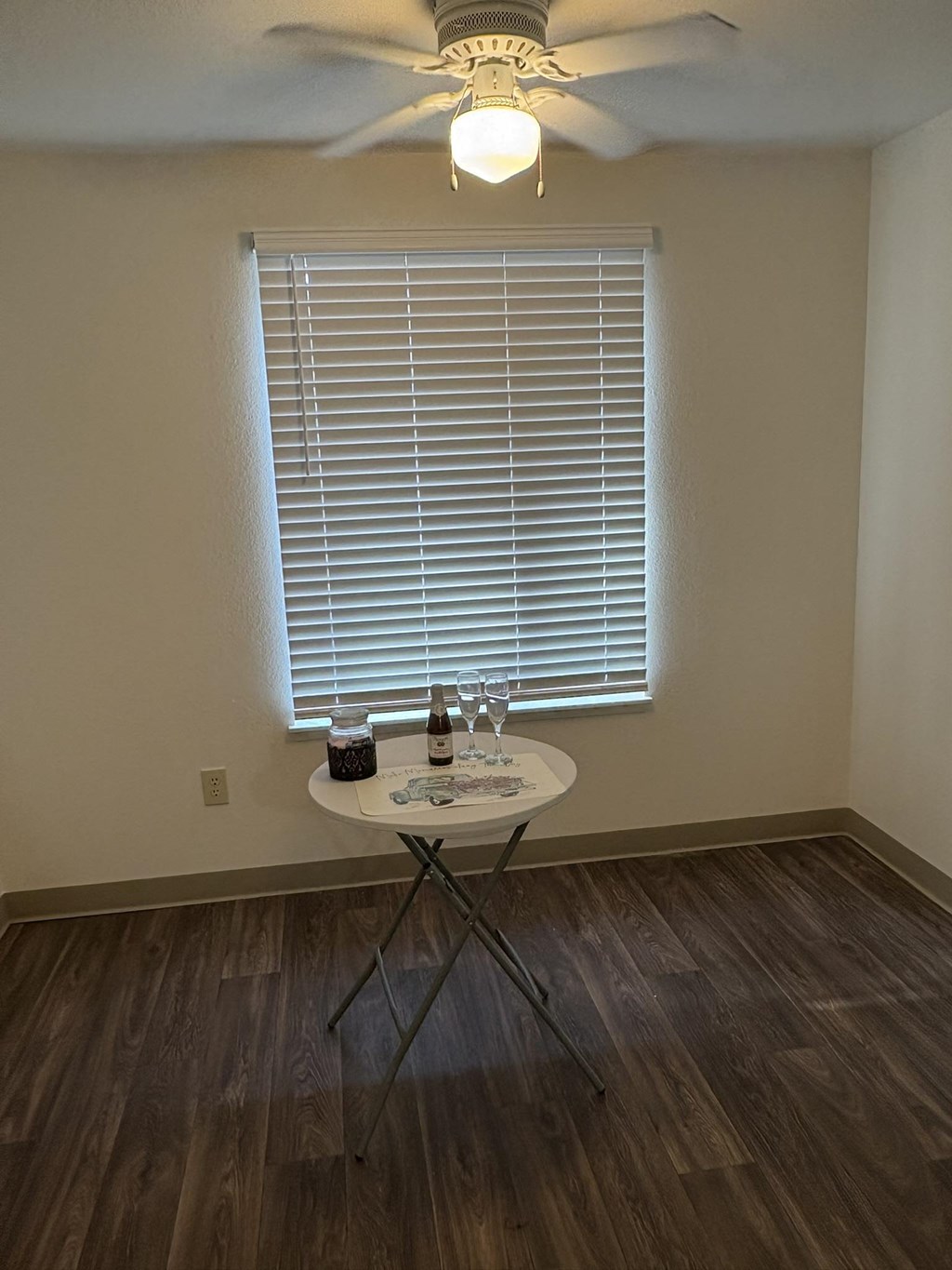 A small round table with a bottle of wine and a glass on it.