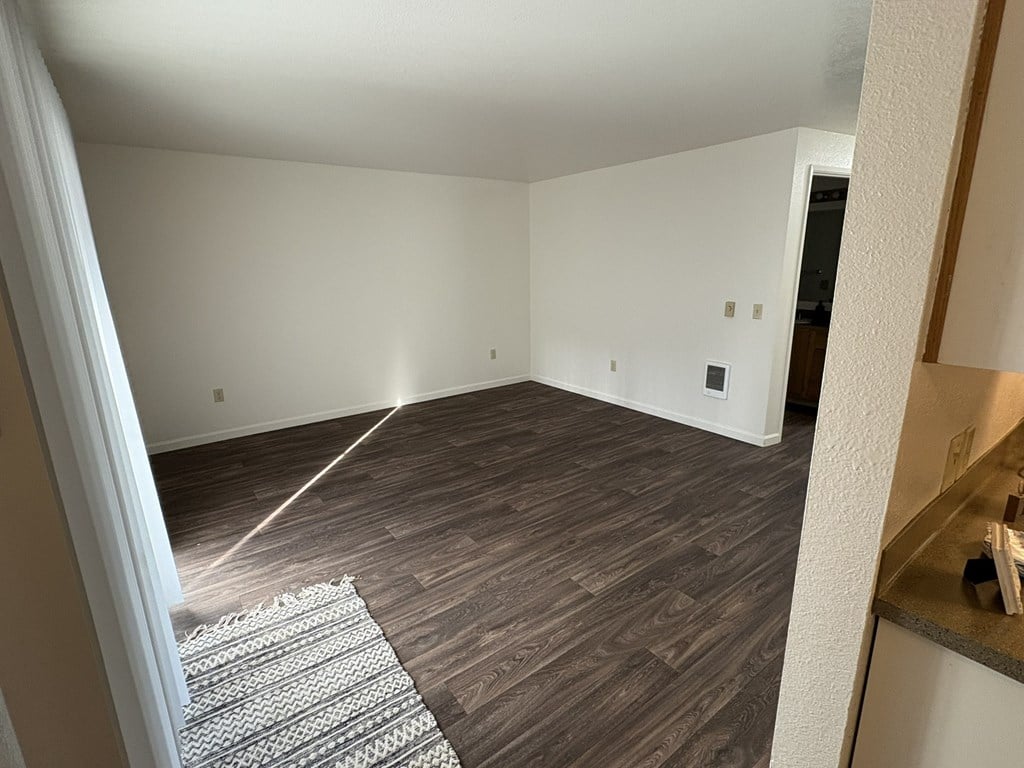 A room with wooden flooring and a rug in the middle.
