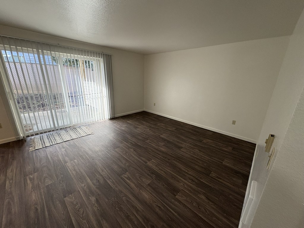 A room with wooden flooring and a window with blinds.
