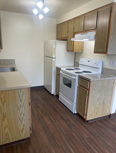 A kitchen with a white stove and wooden cabinets.