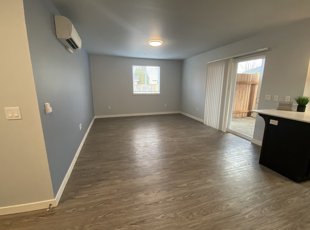 A room with a wooden floor and a window with blinds.