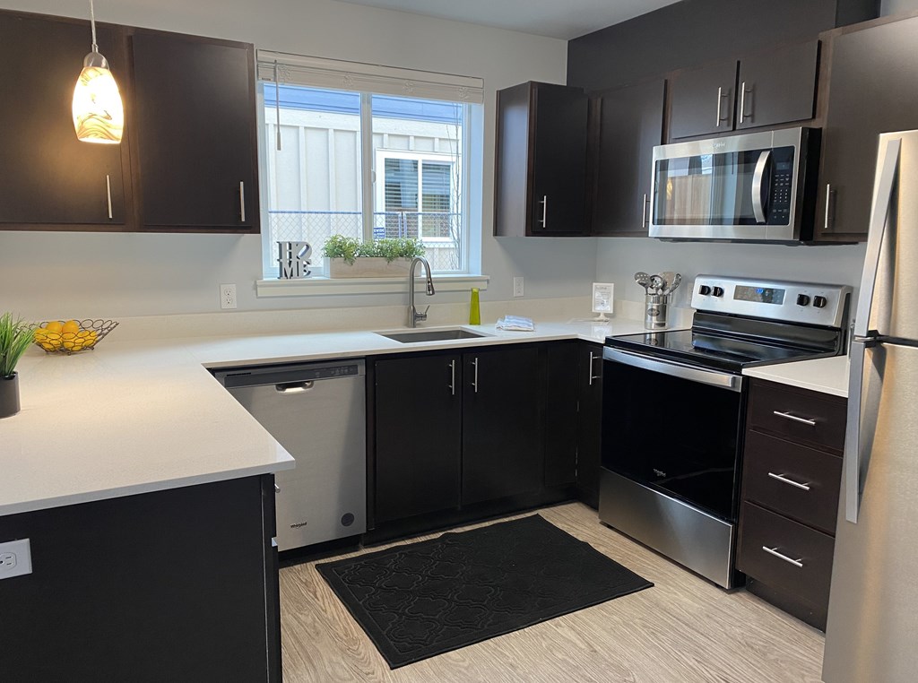 A modern kitchen with black cabinets and stainless steel appliances.